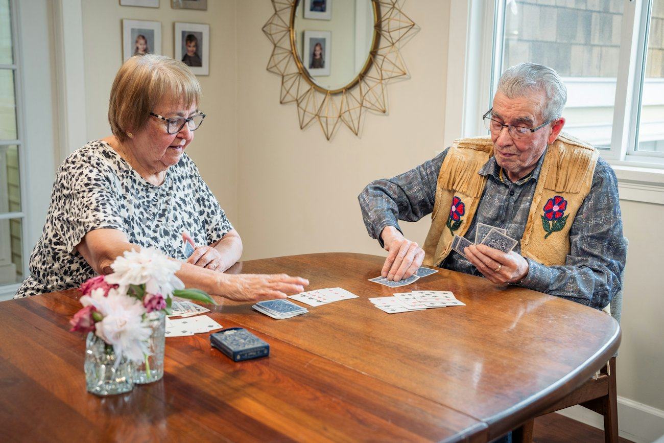 Two older friends playing cards at a dining table